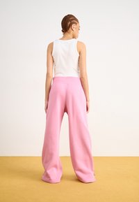 Roze wijde sweatpants met een geribbelde tailleband, gecombineerd met een wit mouwloos topje. Glad materiaal, minimalistisch ontwerp en een relaxte silhouet.
