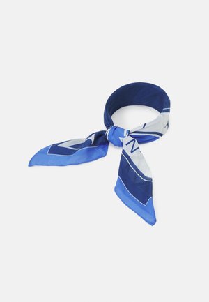 Foulard en soie bleu et blanc à motifs, noué en un nœud lâche sur un fond clair uni.