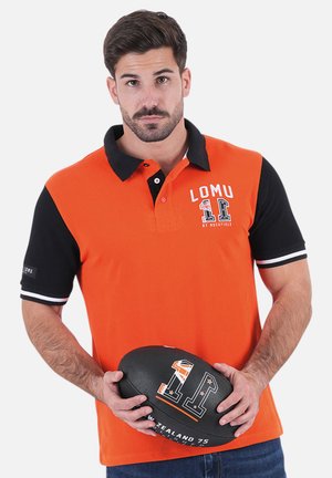 Polo en orange et noir, avec un col, imprimé avec le logo "LOMU 11" et des accents blancs. Un ballon de rugby noir est tenu devant.
