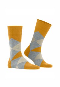 Un paio di calzini a motivi con design geometrici in giallo senape, grigio chiaro e blu. Presentano un polsino a coste e una lunghezza fino al polpaccio.