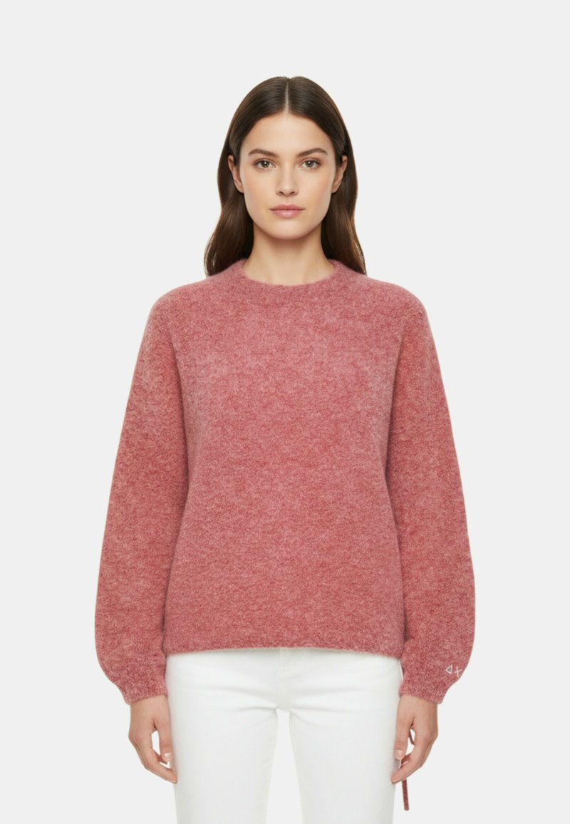 Morbido maglione rosa testurizzato con scollo rotondo e maniche lunghe leggermente arricciate. Presenta una vestibilità ampia e polsini elasticizzati.