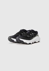 Baskets de sport noires avec une tige en maille, semelle intermédiaire blanche et semelle extérieure noire texturée. Présente un talon renforcé et des accents contrastants.