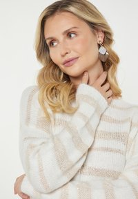 Gebreide trui met witte en beige strepen, met een losse pasvorm en geribde manchetten. Gouden hangers met een iriserende afwerking.