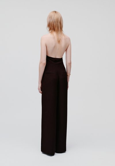 Jumpsuit nero senza schienale con un corpetto aderente e una silhouette a gamba larga; tessuto liscio; design minimalista senza motivi visibili.