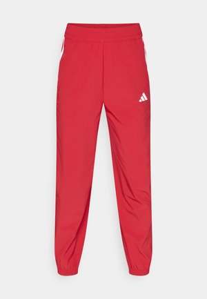Pantalon de sport rouge en tissu léger. Comprend une taille élastique, des chevilles resserrées et des accents de logo blanc sur le côté.