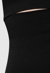 Tessuto nero a coste con un dettaglio sagomato. La texture è liscia e aderente, enfatizzando la forma senza ulteriori decorazioni.