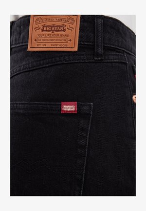 Mustad denim teksad tummates toonides, millel on helepruun nahast sildiga "BIG STAR". Omab punast brändisildi tagumise tasku peal ja vaskseid aksessuaare.