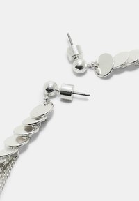 Orecchini a pendente argentati con dischi circolari e dettagli a sfera, rifiniti in metallo lucido e dotati di chiusura a perno per una vestibilità sicura.