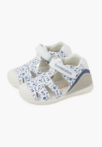 Sandalias infantiles blancas con un patrón azul y blanco de iconos marinos, con tiras ajustables y suela de goma para un buen agarre.