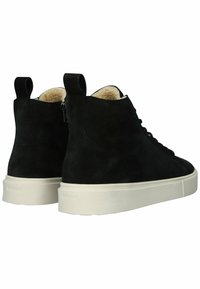 Černé semišové vysoké tenisky mají bílou gumovou podrážku, texturované detaily a měkké krémové podšívky. Obsahují poutka pro snadné obouvání.