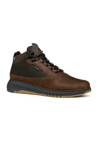 Botas altas de cuero marrón con acentos de malla negra, punta redondeada, cordones negros, suela de goma y tirador trasero. Cuenta con un collar acolchado.