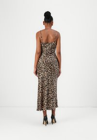 Leopard print midi dress with thin straps, fitted silhouette, and a flared hem, made from smooth fabric; paired with black high-heeled shoes.