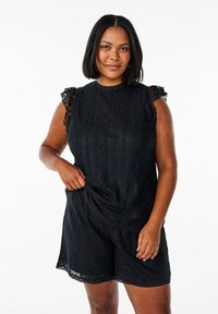 Czarny koronkowy kombinezon z krótkim rękawem i koronkowym wykończeniem, okrągłym dekoltem oraz luźnym krojem, w który wpleciony jest falisty wzór.