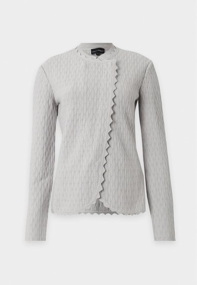 Veste à manches longues gris clair texturée, à motif vertical ondulé et bord avant asymétrique festonné, exposée sur fond blanc.