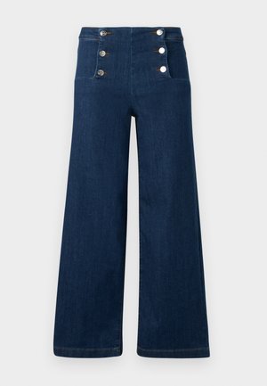 Temno modre kavbojke širokih hlačnic z visokim pasom in dvema navpičnima vrstama srebrnih gumbov spredaj.