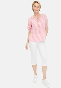 Roze en witte gestreepte blouse met puffed sleeves en een strik aan de voorkant. Gecombineerd met witte capri-broeken en witte sneakers. Eenvoudig ontwerp.