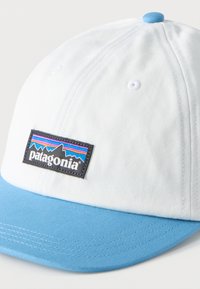 Άσπρο και φωτεινό γαλάζιο καπέλο μπέιζμπολ με πολύχρωμη παράσταση λογότυπου Patagonia στην μπροστινή πλευρά.
