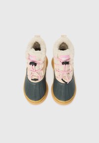 Wasserdichte Stiefel mit einer grünen Gummisohle, beigem gepolstertem Obermaterial, rosa Schnürsenkeln und einer strukturierten, tanfarbenen Sohle. Eine Fleece-Fütterung ist innen sichtbar.