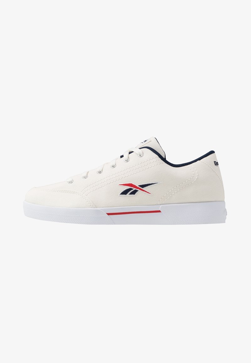 Zapatilla de lona blanca con acentos en azul y rojo, que presenta seis ojetes, cordones planos, una suela acolchada y un logo en el costado.