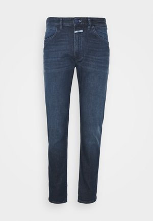 Jeans de mezclilla azul oscuro con un corte ajustado. Cuenta con dos bolsillos frontales y un cierre clásico de botón y cremallera. Textura suave con un desvanecimiento mínimo.