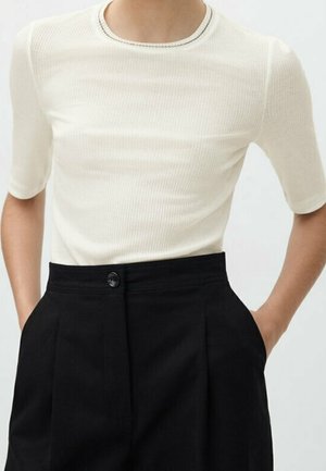 Top bianco a maniche corte con collo rotondo e lavorazione a coste, abbinato a pantaloni neri a vita alta con un solo bottone e design plissettato.