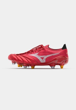 Red soccer cleat with a textured upper, featuring white accents, slim design, and yellow and clear studs on the outsole for grip.