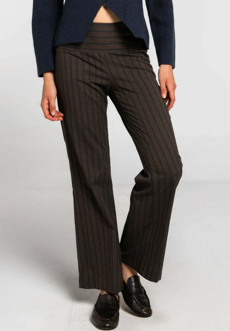 Pantalons rayés bruns avec une taille haute, fabriqués à partir d'un tissu texturé. Les pantalons sont à jambes larges avec une coupe décontractée, complétés par des mocassins noirs.