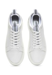Baskets en cuir blanc avec lacets, présentant une texture lisse, un orteil arrondi et une boucle d'accent grise au niveau du talon.