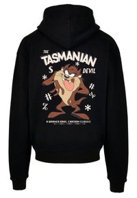 Svart hettegenser med et grafisk bilde av Tasmanian Devil-karakteren, med fet hvit tekst over og fargerike detaljer rundt designet.
