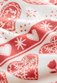 Rot-weißer Fleece-Stoff mit Herz- und Schneeflockenmuster, einer weichen, strukturierten Oberfläche und dekorativen Rändern.