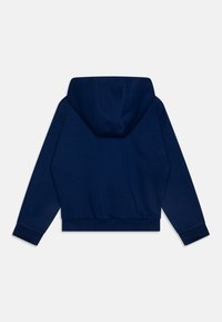 Sötétkék kapucnis póló, amely cropped fazonú, bordázott aljjal és mandzsettákkal, puha tapintású és sima felületű. A hátsó nézeten látható a kapucni és az varrások.