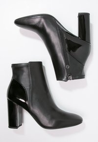 Czarne botki za kostkę o błyszczącej, lakierowanej wykończeniu, o spiczastym nosku i 4-calowym słupkowym obcasie. Bok z zamkiem błyskawicznym dodaje wizualnego zainteresowania. Gładka skóra.