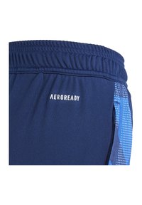 Gros plan sur un short de sport bleu marine avec taille élastique, logo "AEROREADY" et poche latérale avec une bordure en motif numérique bleu.