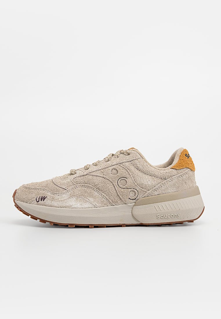 Sneaker in suede beige con una toma superiore testurizzata, dotata di una soletta imbottita e suola in gomma marrone; include accenti del logo e chiusura con lacci.