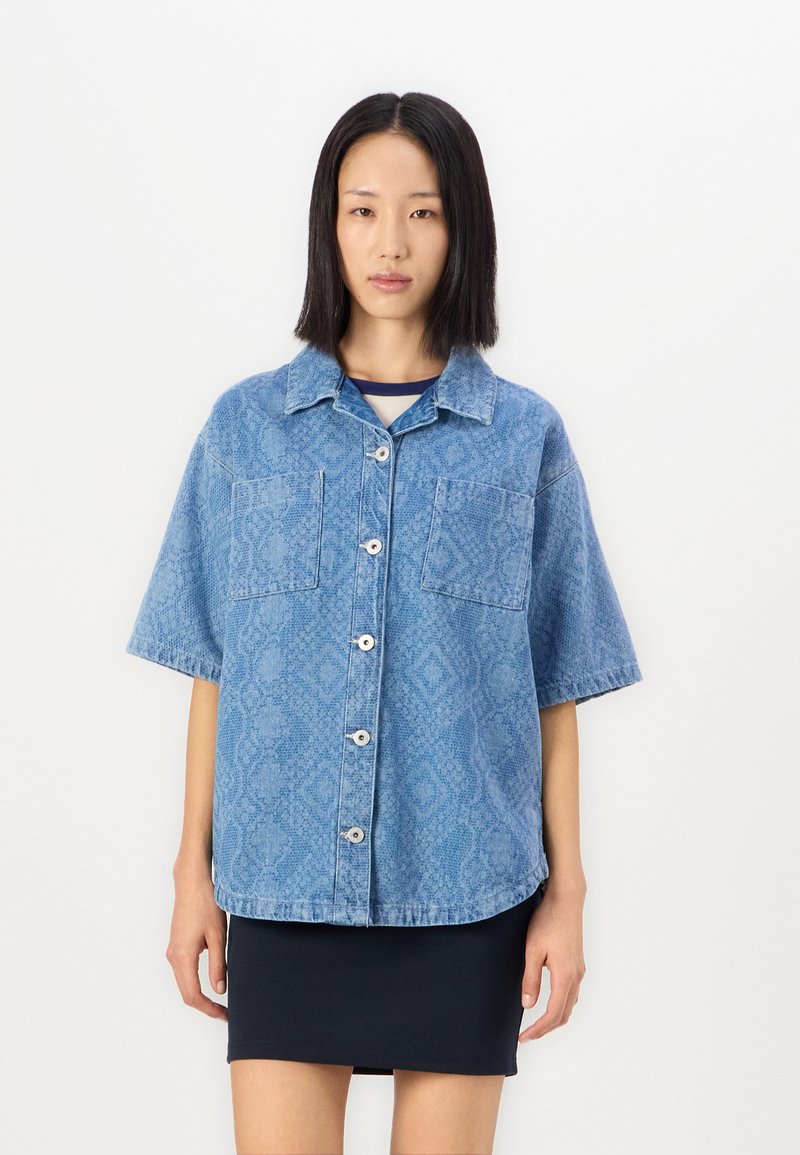 Cămașă din denim albastru, cu mânecă scurtă, cu model în romb, două buzunare pe piept, închidere cu nasturi și croială lejeră. Textură netedă, design casual.