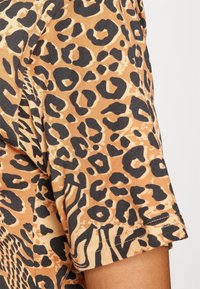 Leopardprint kortærmet skjorte i nuancer af brun og sort, fremstillet i et blødt, tekstureret stof med en afslappet pasform og opkrøllede ærmer.