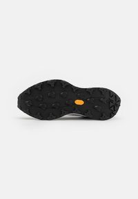 Semelle en caoutchouc noir avec des crampons multidimensionnels pour une traction optimale. Présente un logo Vibram orange; texture lisse avec un motif robuste.