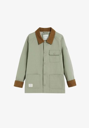 Groene canvas jas met een bruine corduroy kraag en manchet, voorzien van twee voorkruisen en een gemarkeerd label. Drukknoopsluiting.