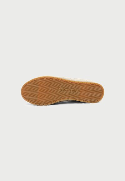 Semelle de chaussure avec un motif en chevrons et le nom de la marque "Paul Smith" embossé au centre sur un fond clair.