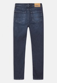 Jeans de mezclilla azul oscuro con un corte slim, que cuentan con dos bolsillos traseros, costuras en contraste y una etiqueta de cuero marrón en la cinturilla.