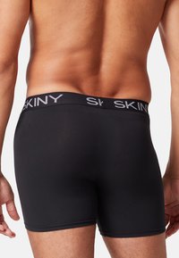 Boxer in cotone nero realizzati in materiale liscio, con una ampia vita elastica riportante il nome del marchio "SKINY" in lettering bianco.