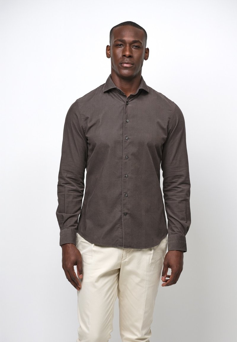 Camicia button-up marrone con una texture liscia, vestibilità slim e maniche lunghe, abbinata a pantaloni color crema.