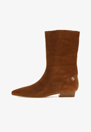Botte mi-mollet en daim marron avec bout pointu, petit talon empilé bas et petit détail de logo doré près du talon.