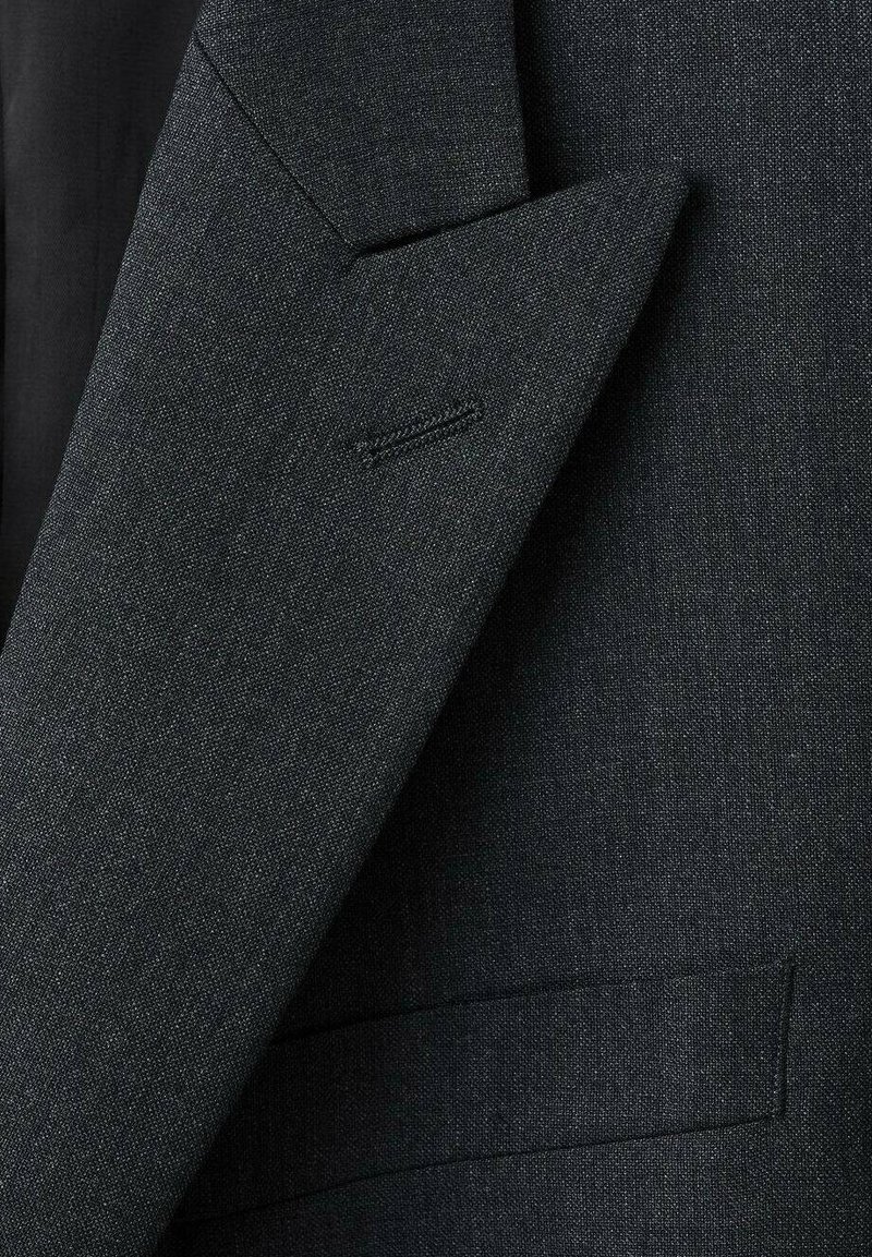 Blazer grigio scuro in tessuto texturizzato. Presenta un revers a lancia, design monopetto e un motivo tessuto sottile.