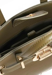Groene leren handtas met een gestructureerde vorm, voorzien van gouden hardware, een magnetische sluiting en een interieur met meerdere compartimenten.