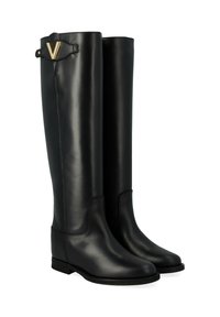 Bottes en cuir noir jusqu'au genou avec une finition lisse, présentant un accent en forme de V doré près du haut et une semelle plate et basse.