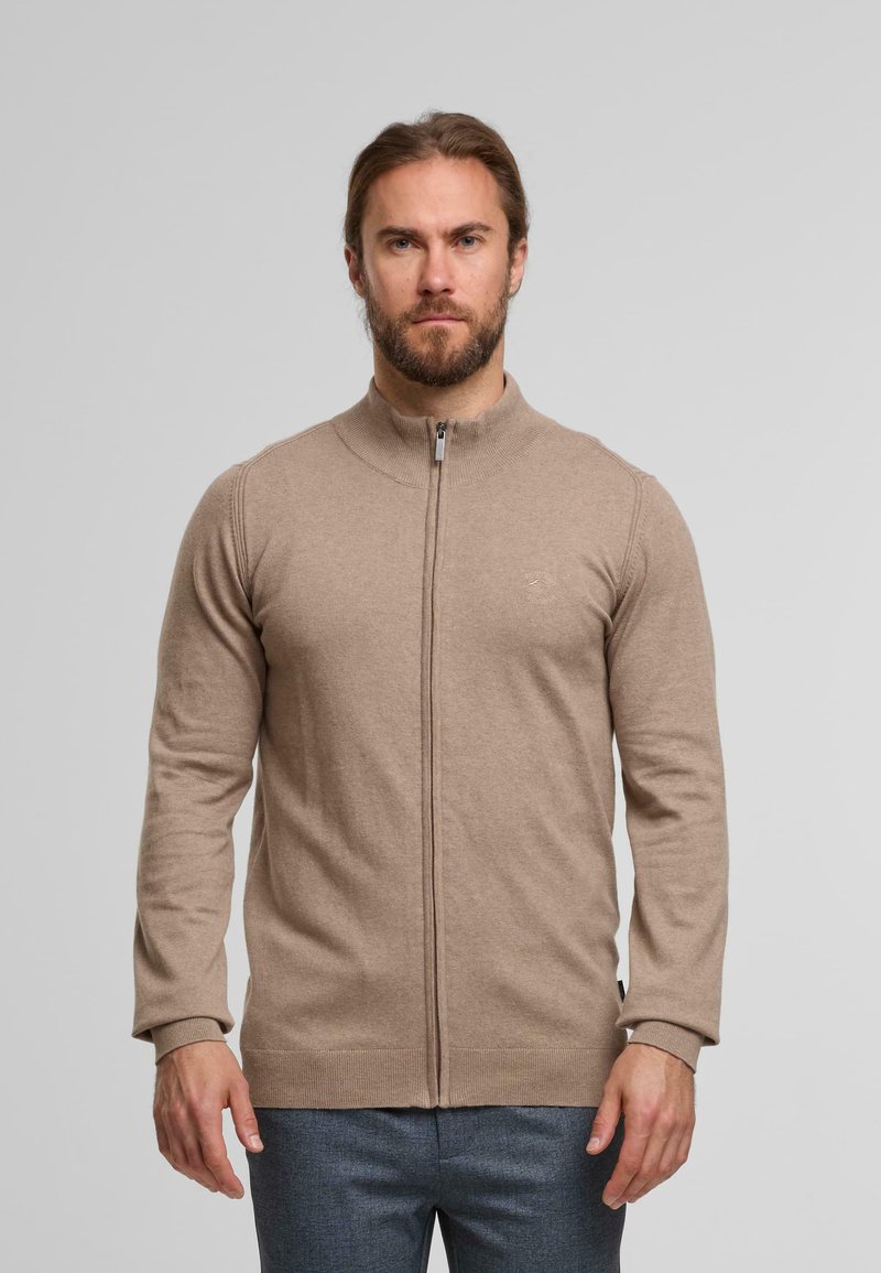 Maglione beige con zip, colletto alto, polsini a coste e una texture liscia. Presenta un logo sottile sul petto e una silhouette dritta.