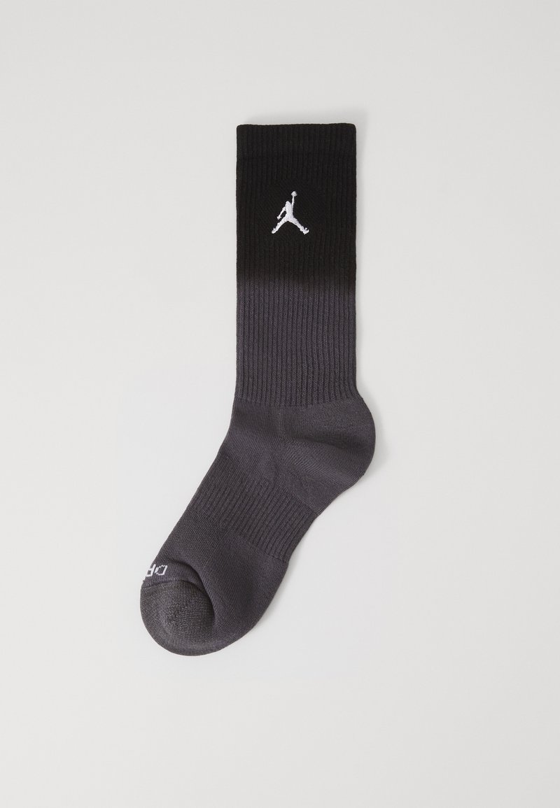 Calzini sportivi neri con texture a coste, caratterizzati da un logo Jumpman bianco nella parte superiore e una sfumatura graduale verso un grigio più scuro sulla punta.