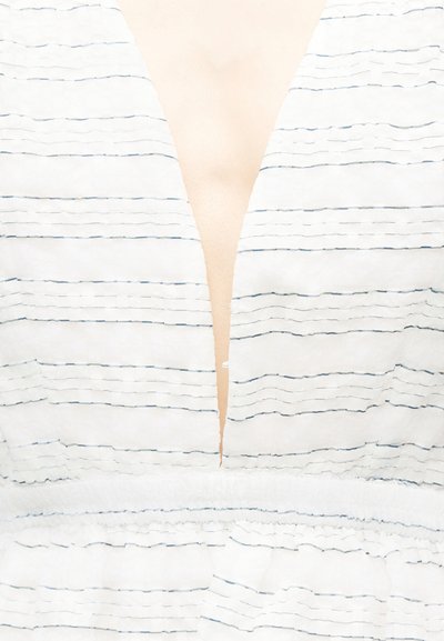 Λευκό ύφασμα με λεπτές οριζόντιες μαύρες ρίγες και βαθύ V-λαιμόκοψη που αφήνει ακάλυπτο το δέρμα στο κέντρο.