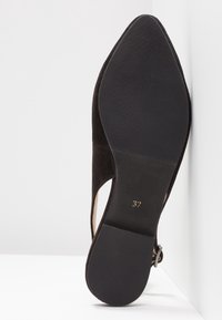 Chaussure à talon haut en suede noir avec un bout pointu, des côtés découpés et une semelle en caoutchouc texturé. Taille indiquée comme 37.